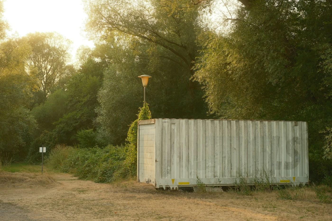 A shipping container placed on a level, clear spot on a rural property